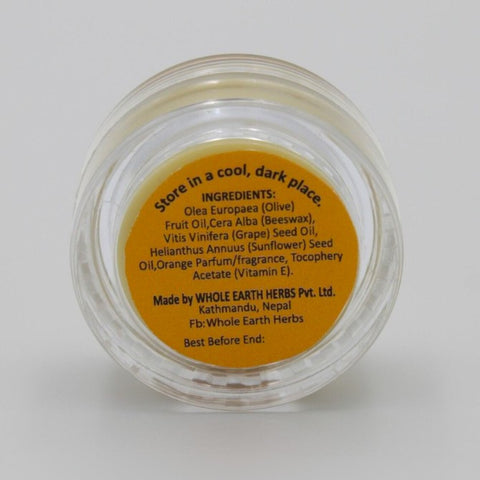 House of Nepal orange lip balm in a clear jar with orange label listing ingredients like olive oil, grape seed oil, beeswax, and vitamin E.