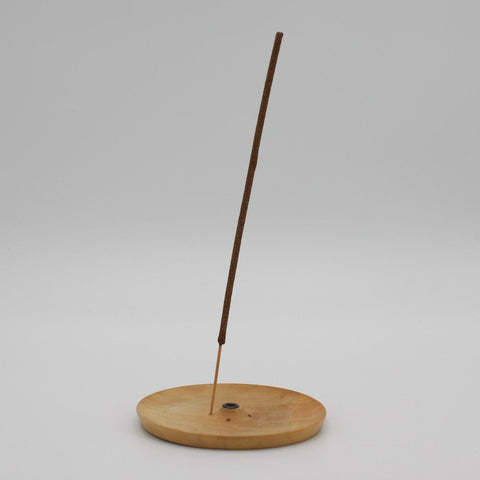 House of Nepal Räucherstäbchenhalter aus hellem Holz mit einfacher, runder Form und einem brennenden Räucherstäbchen.