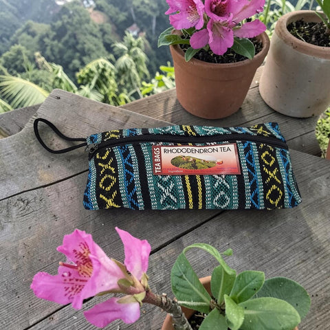 House of Nepal Himalayan Rhododendron Tea in a reusable woven pouch with black trim and zipper. Features a colorful geometric pattern.