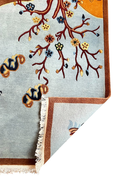 House of Nepal handgeknüpfter tibetischer Wollteppich 120x190 cm, hellblau mit braunem Rand und floralem Muster