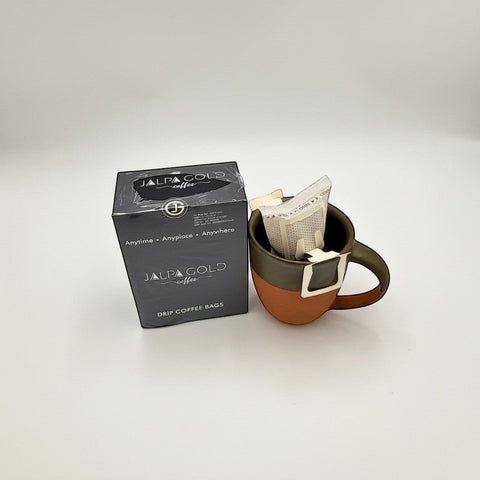 House of Nepal Jalpa Gold drip coffee bags in a rustic brown and green mug, micro-ground Arabica for intense flavour.